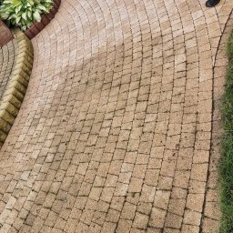 Kam-Dach Kamil Parczewski - Kaskadowo ułożona kostka brukowa w odcieniach beżu, tworząca ścieżkę ogrodową z elementami zieleni i oświetleniem. Widok z góry, podkreślający wzór ułożenia.