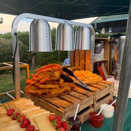 Szulta Catering - Bufet z podgrzewaczami: naleśniki z truskawkami, frytki, nuggetsy. Drewniane skrzynki, sosy i dżem. Catering plenerowy pod namiotem.