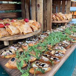 Szulta Catering - Elegancki catering: kanapki z rukolą, roladki z sezamem i truskawkami na drewnianych paterach i skrzynkach. Ujęcie z bliska, bogata ekspozycja.