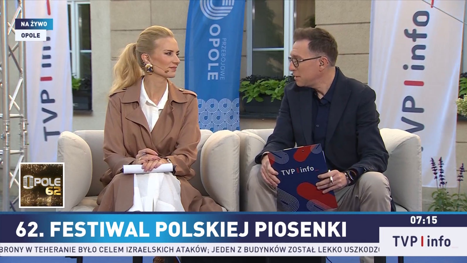 Dwoje prezenterów siedzi na kanapie podczas 62. Festiwalu Polskiej Piosenki w Opolu, w tle banery TVP Info i Opole.