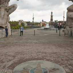 ARTISAN ALEKS COMPANY - Tematyczny park rozrywki: centralny plac z fontanną, latarnią morską i rzeźbami mitologicznych postaci. Brukowana nawierzchnia z dekoracyjnym elementem centralnym.