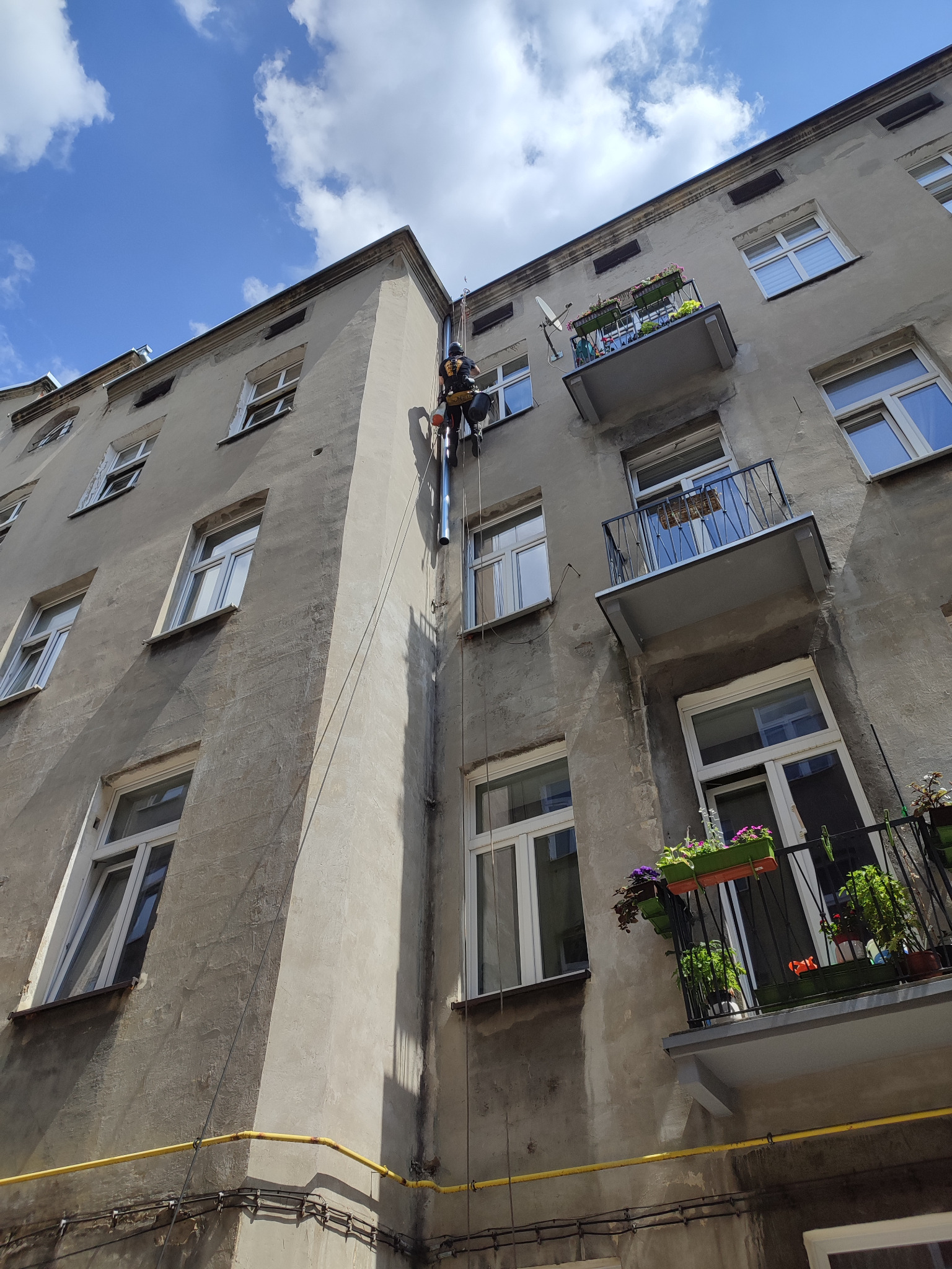 Montaż rur spustowych na kamienicy.