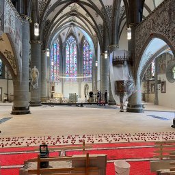 Kacbud - Wnętrze kościoła w trakcie remontu posadzki: czerwona mata grzewcza, poziomowanie pod płytki, kolumny, witraże. Prace wykończeniowe w zabytkowym obiekcie sakralnym.