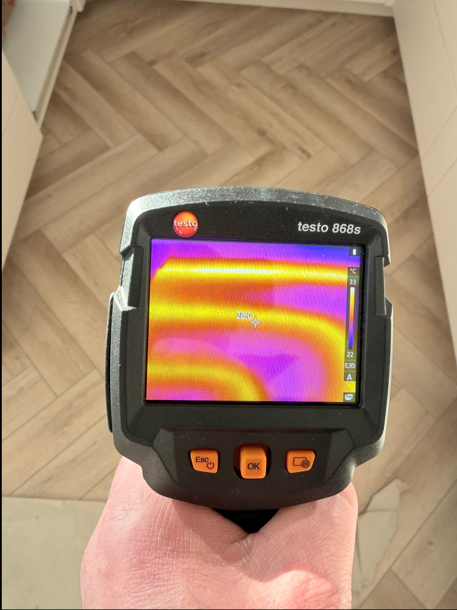 Termowizja podłogówki w trakcie pomiaru kamerą Testo 868s. Widoczne rozłożenie ciepła na parkiecie w jodełkę. Pomiar temperatury 28 stopni Celsjusza.