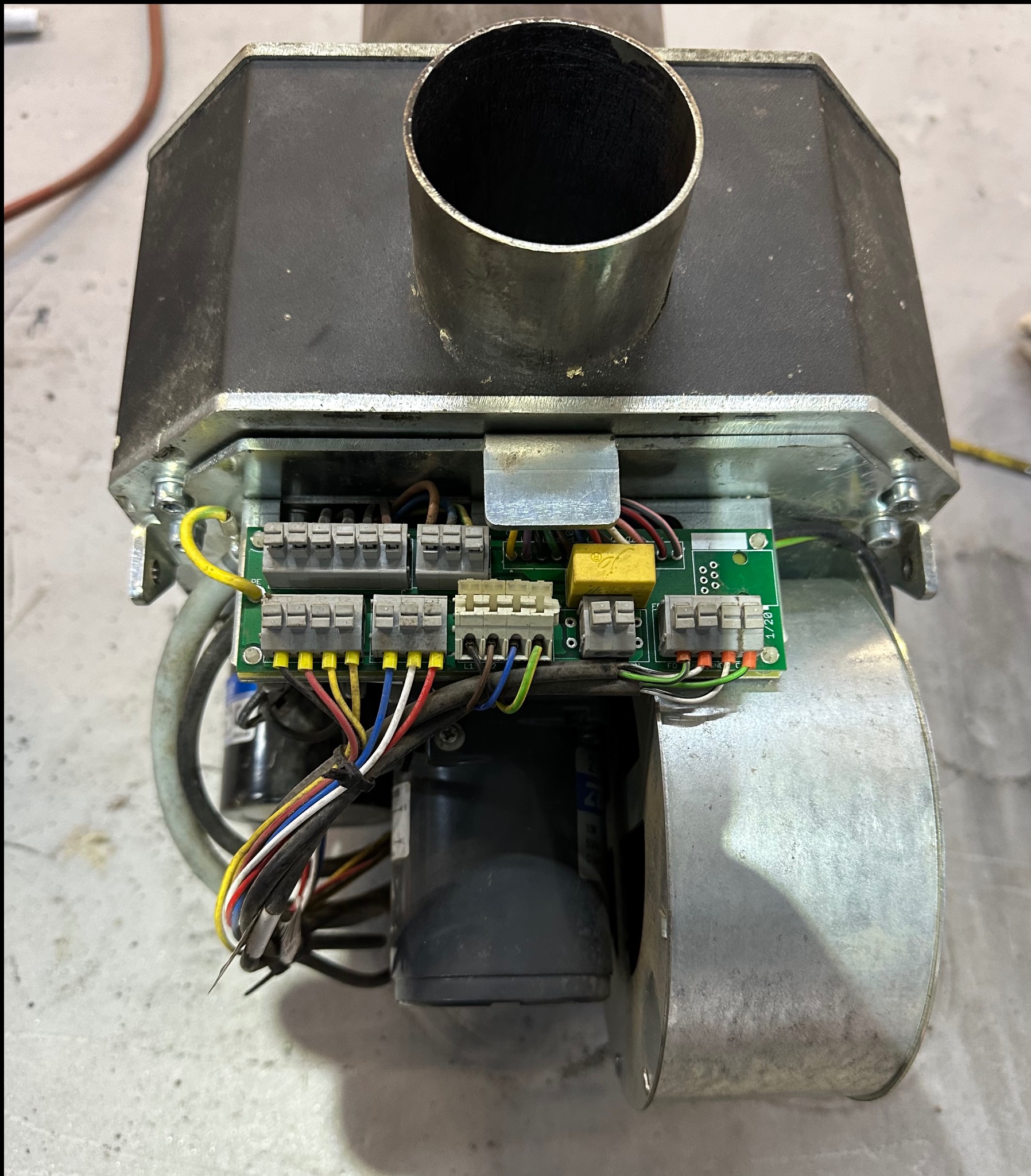 Otwarta obudowa pieca z widoczną płytką sterującą, złączami elektrycznymi i przewodami. Element instalacji grzewczej w trakcie montażu lub serwisu.