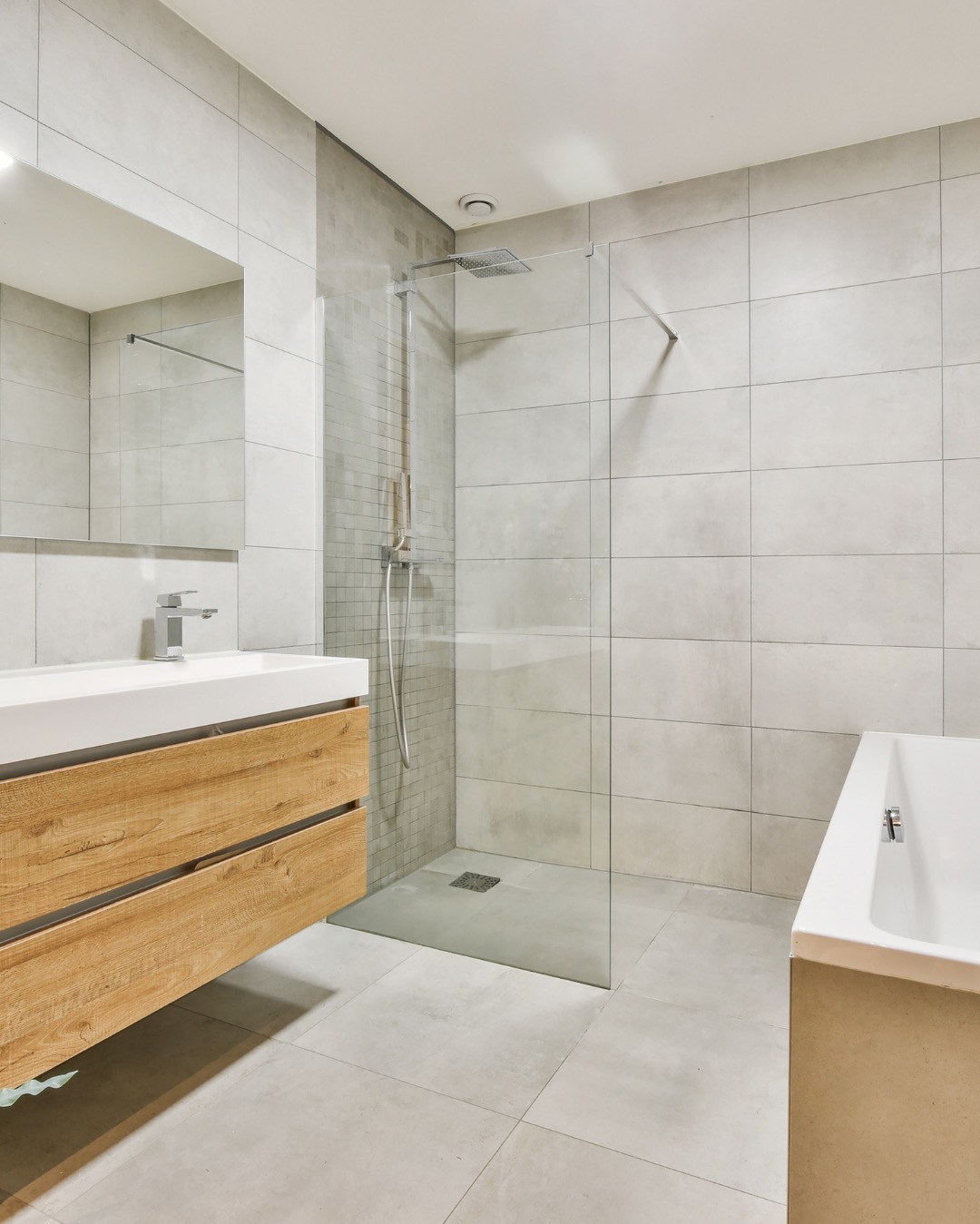 Nowoczesna łazienka z kabiną typu walk-in i drewnianą szafką pod umywalką w Lesznowoli. Jasne płytki i minimalistyczny design.