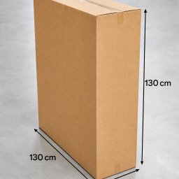 BOX-MASTER - Wysoki, prostokątny karton z taśmą, o wymiarach 130x130x30 cm, stoi na szarym betonowym podłożu. W tle widoczne fragmenty drewnianych palet.