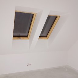 JankoBud - Białe poddasze z dwoma oknami dachowymi w drewnianych ramach. Świeżo pomalowane ściany i gładka podłoga w Limanowej. Widoczne gniazdka elektryczne.