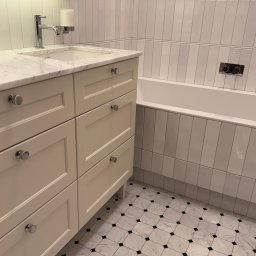 Joanna Lafuite-Tomaszewska we do design pl - Jasna łazienka z marmurową umywalką, białymi płytkami ułożonymi pionowo i podłogą w biało-czarną szachownicę. Bateria umywalkowa chromowana, minimalistyczna.