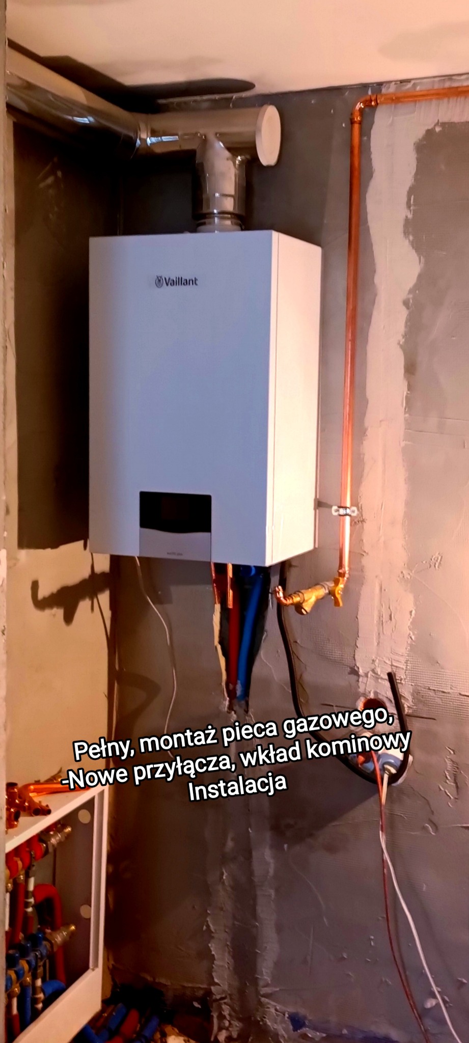 Montaż pieca gazowego Vaillant z nowymi przyłączami i wkładem kominowym na tle surowej ściany. Widoczne miedziane rury i instalacja.
