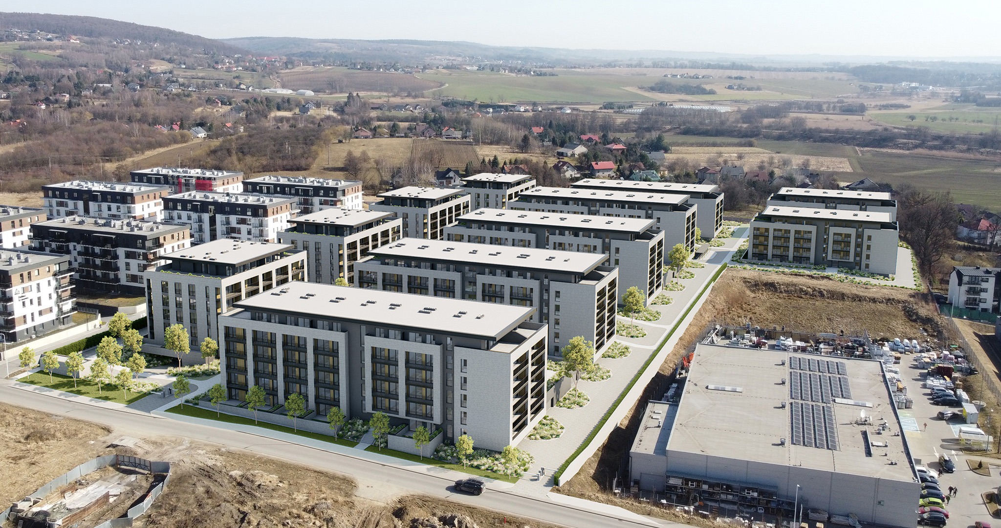 Kompleks nowoczesnych, wielokondygnacyjnych budynków mieszkalnych z płaskimi dachami, widoczny z lotu ptaka na tle pagórkowatego krajobrazu i infrastruktury miejskiej.
