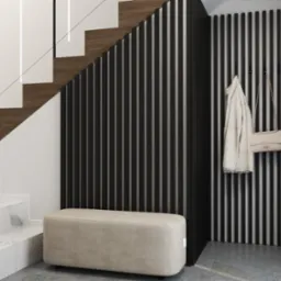 Nowoczesny przedpokój z marmurowymi schodami, drewnianymi stopniami i czarnymi lamelami. Beżowa pufa i dodatki tworzą spójną całość.