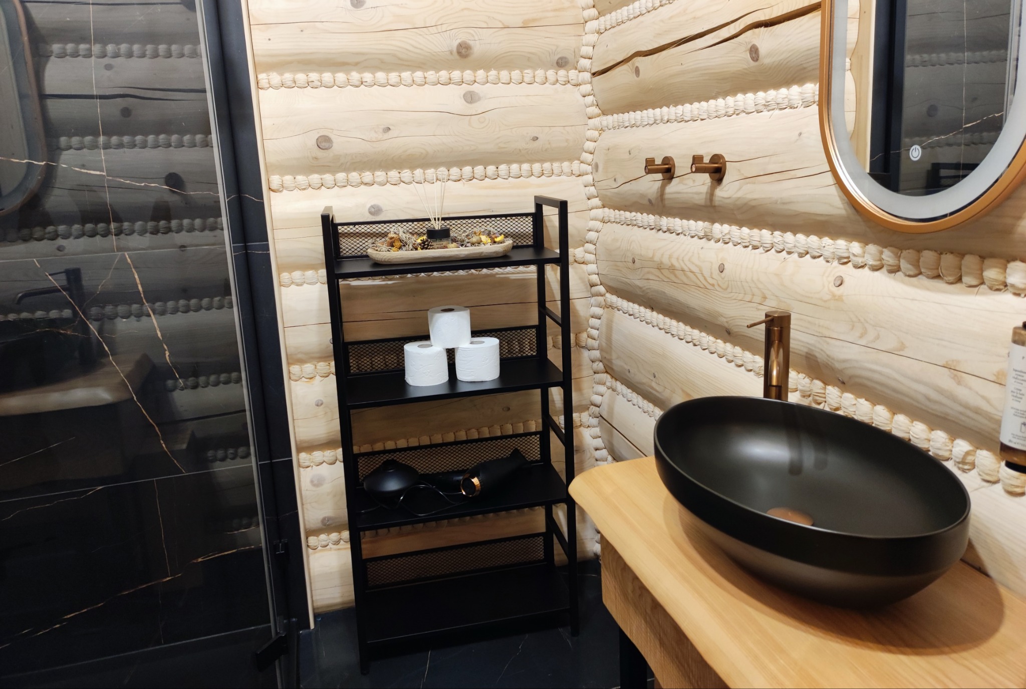 Nowoczesna łazienka w stylu góralskim: czarna umywalka nablatowa, drewniane ściany, czarny regał z akcesoriami. Ukończone sprzątanie, gotowe do użytku.