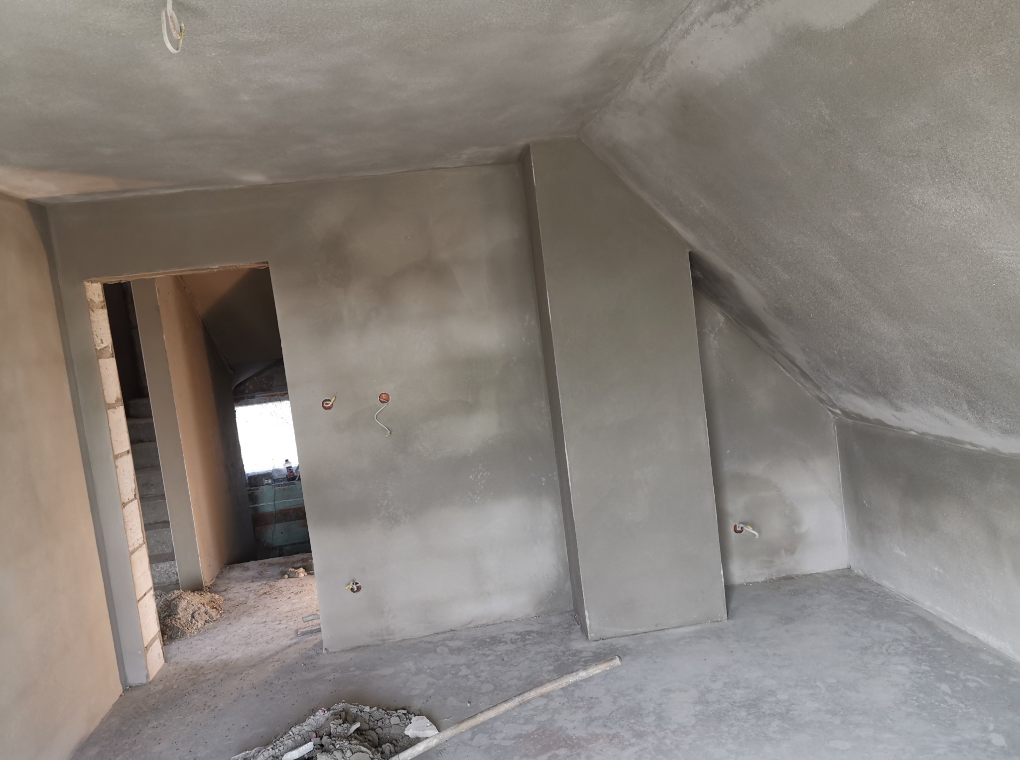 Świeżo położone tynki maszynowe w Karczmiskach Pierwszych, widoczne gładkie ściany i sufit na poddaszu, przygotowane do dalszych prac wykończeniowych.