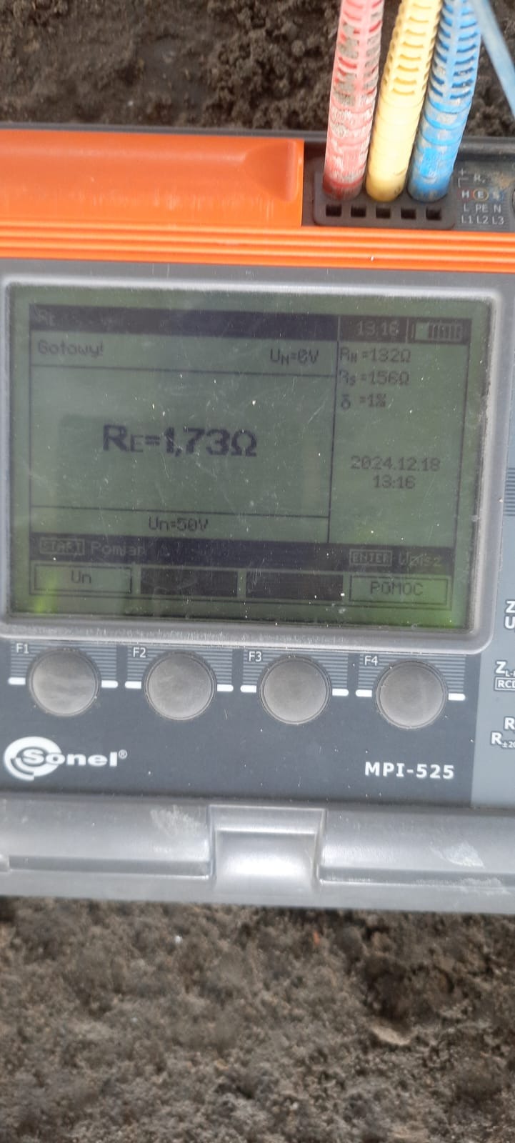 Miernik Sonel MPI-525 z podłączonymi przewodami, wyświetlający wynik pomiaru rezystancji uziemienia Re=1,73Ω. Widoczny ekran z datą i godziną pomiaru.