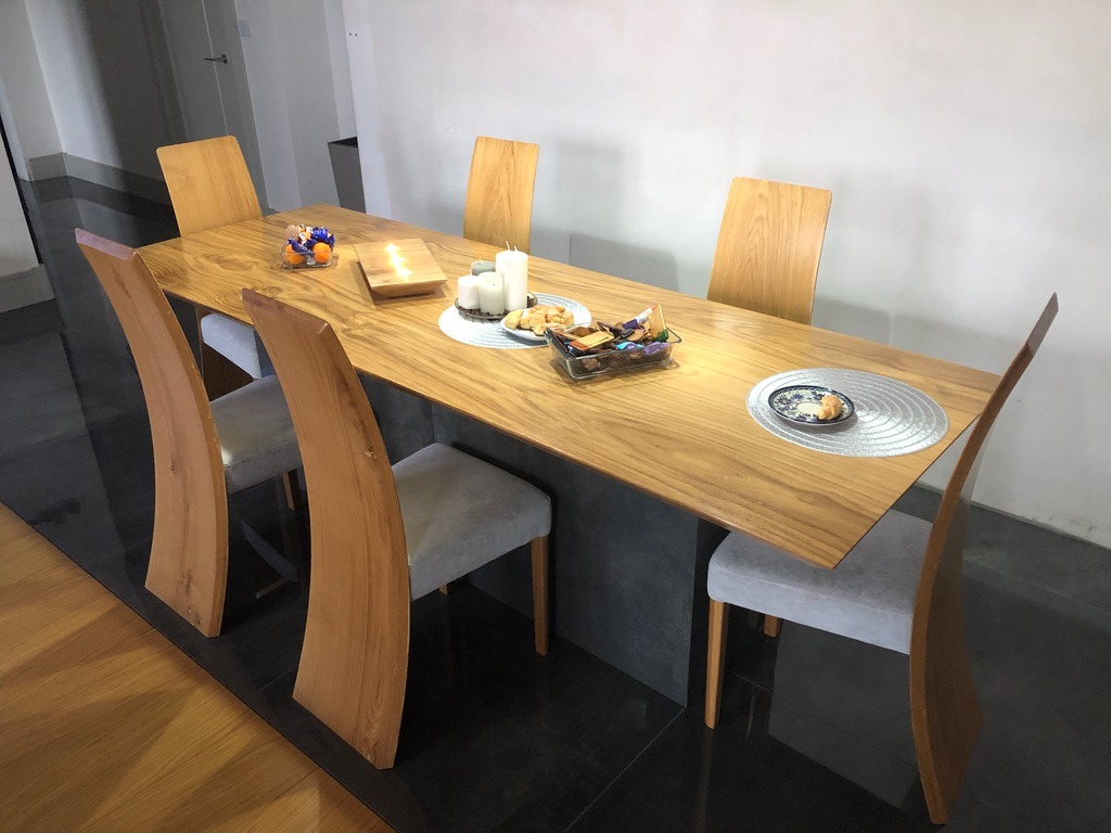 Drewniany stół z krzesłami o nietypowych, wygiętych oparciach. Na blacie dekoracje, talerze i przekąski. Nowoczesny design.