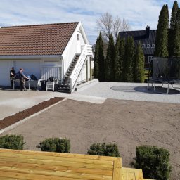 Paweł Szopiński - Przygotowany teren pod trawnik z obrzeżami, widoczne budynki gospodarcze i trampolina. Dwóch mężczyzn przy pracy na zewnątrz.