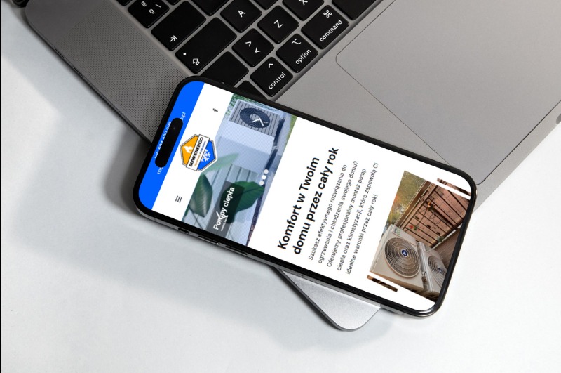 Smartfon wyświetla stronę internetową buw-energo.pl z ofertą pomp ciepła, leżący na klawiaturze laptopa.
