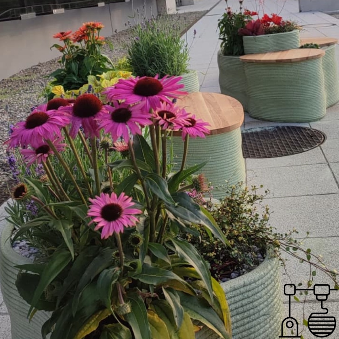 Zestaw mebli ogrodowych: donice z kwiatami i stoliki z drewnianymi blatami, wykonane w technologii druku 3D. Charakterystyczna tekstura warstw. Ujęcie z bliska.