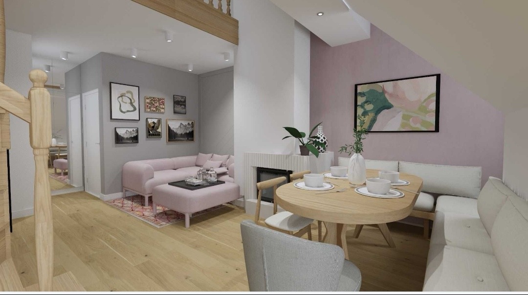 Jasne, przestronne wnętrze z różową sofą i drewnianym stołem. Na ścianach grafiki. Widok z perspektywy schodów. Nowoczesny design z elementami klasycznymi.