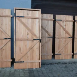 Drewniane bramy garażowe z ukośnymi wzmocnieniami i czarnymi okuciami, ustawione na kostce brukowej przed budynkiem.