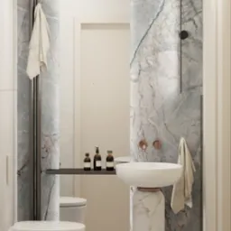 Elegancka łazienka z marmurowymi akcentami: umywalka na postumencie, toaleta podwieszana, grzejnik drabinkowy i armatura w kolorze różowego złota.