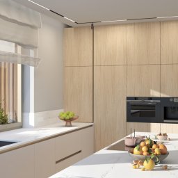 ZMYSŁ WNĘTRZA Architektura Roksana Simińska - Jasna kuchnia z drewnianymi frontami szafek, białym blatem i wyspą. Na wyspie owoce w misie. Okno z widokiem na zieleń. Minimalistyczny design, nowoczesne oświetlenie.