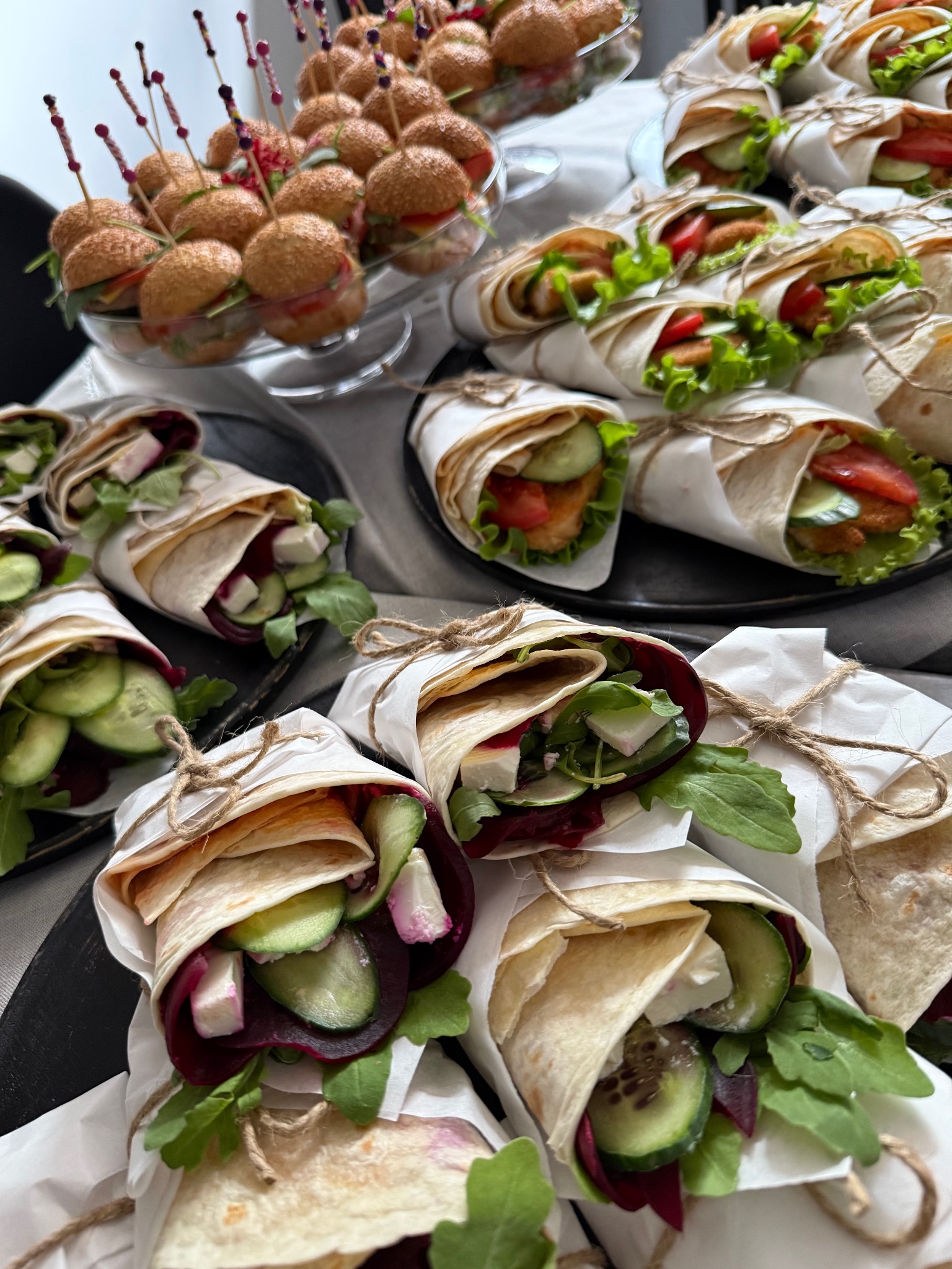 Dekoracyjne wrapy z warzywami i mini burgery na szklanej paterze, catering na przyjęcie, widok z góry, naturalne światło.