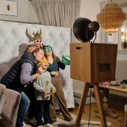 RIVER SPÓŁKA Z OGRANICZONĄ ODPOWIEDZIALNOŚCIĄ - Rodzinne zdjęcie w fotobudce retro z rekwizytami: hełmy wikingów, maski i okulary. W tle dekoracyjna ściana i żyrandol.