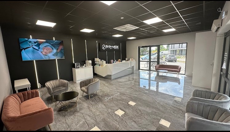 Nowoczesne wnętrze salonu kosmetycznego: recepcja, strefa oczekiwania z fotelami i TV prezentującym zabieg, czarno-biała kolorystyka, marmurowa podłoga.