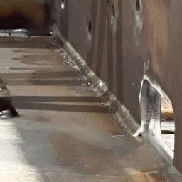 A.D.WELDER SPÓŁKA Z OGRANICZONĄ ODPOWIEDZIALNOŚCIĄ - Wnętrze konstrukcji stalowej z widocznymi spawami i otworami. Metal surowy, bez wykończenia, z detalami spoin i śladami po obróbce. Ukazane z bliska, z perspektywą od dołu.