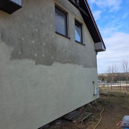 Patrex Patryk Bejynka - Elewacja domu w trakcie czyszczenia. Widoczne różnice w kolorze i zabrudzeniach przed i po myciu. Żółty wąż leży na ziemi.
