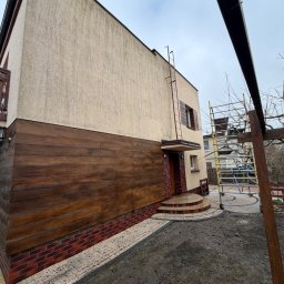 Patrex Patryk Bejynka - Dom z elewacją częściowo wyczyszczoną, z widocznymi rusztowaniami. Dolna część elewacji wykończona drewnem. Widoczny efekt czyszczenia elewacji.