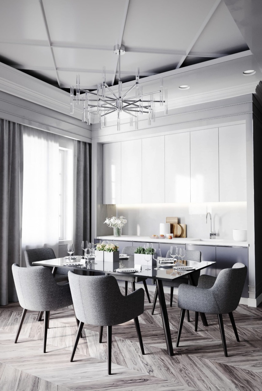 Nowoczesna jadalnia z szarymi krzesłami, szklanym stołem i designerskim żyrandolem. Parkiet w jodełkę i minimalistyczna zabudowa kuchenna w tle.