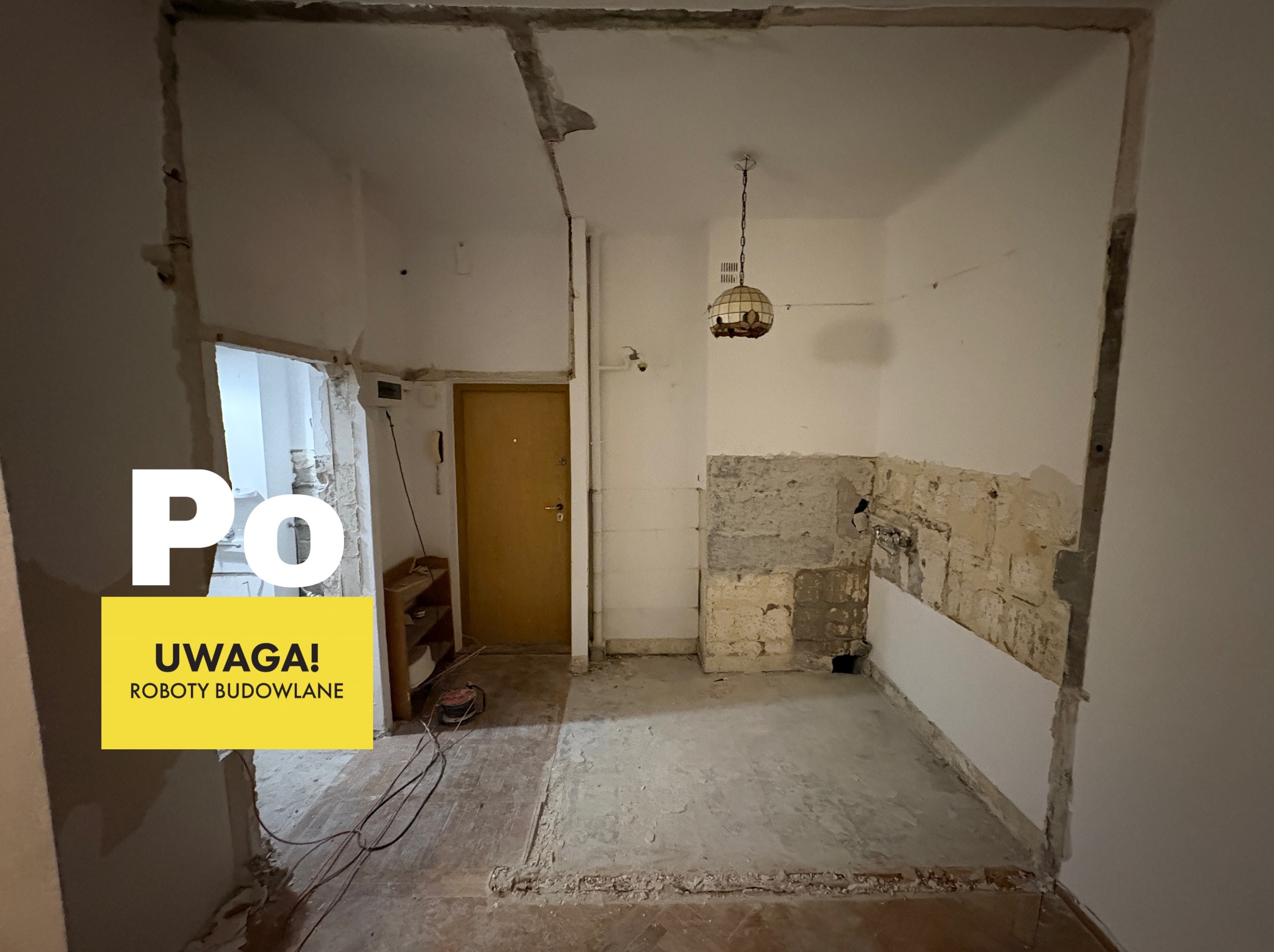 Wnętrze po demontażu ścian, z widocznymi śladami po instalacjach i fragmentami starej zabudowy. Na pierwszym planie napis 'PO' i żółty baner 'UWAGA! ROBOTY BUDOWLANE'.