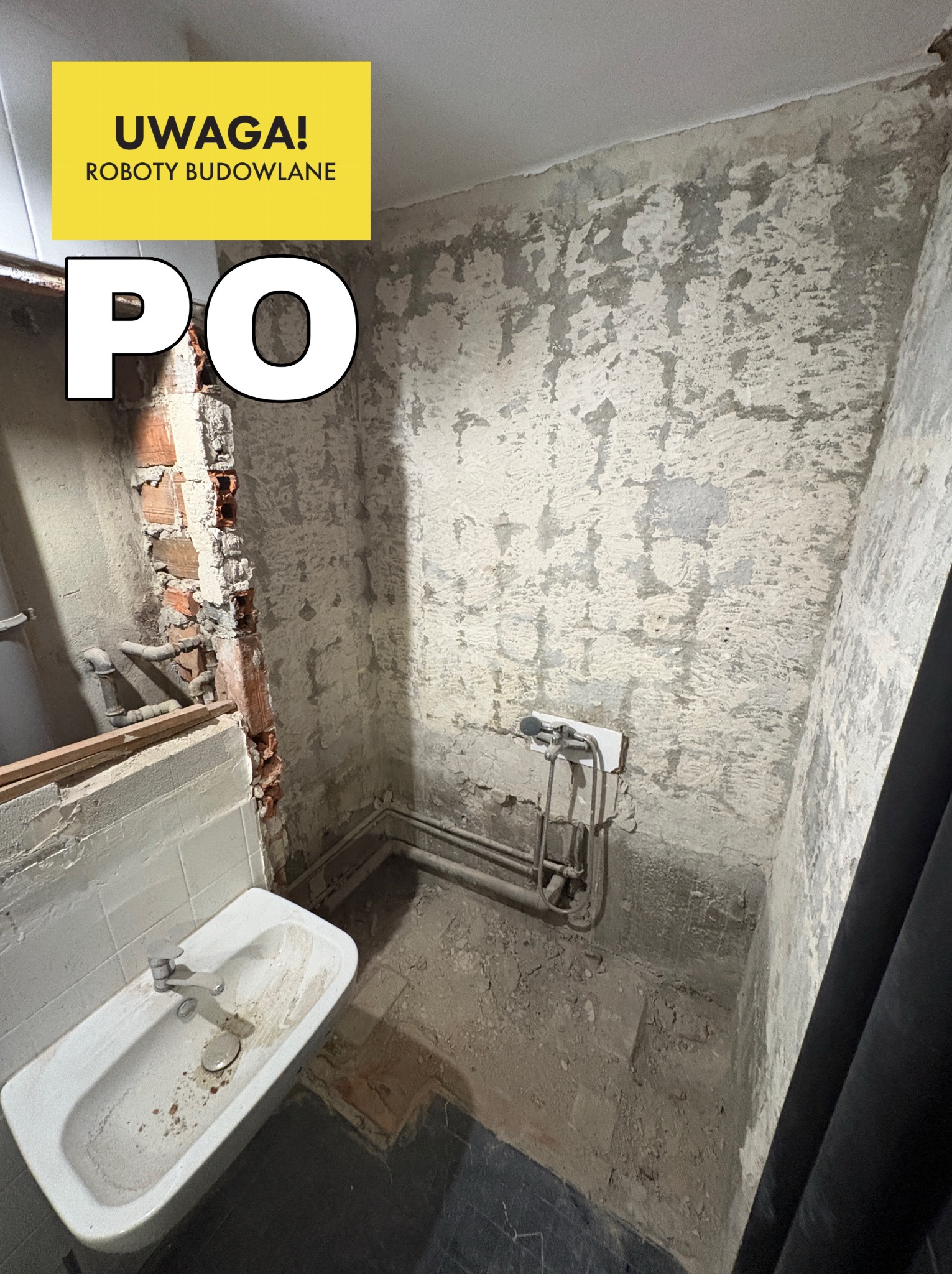 Łazienka po usunięciu płytek i części ściany, widoczne instalacje. Umywalka i rury na ścianie. Na górze żółty baner z napisem 'Uwaga! Roboty budowlane' i 'PO'.