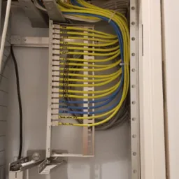 Szczegółowe ujęcie wnętrza szafy elektrycznej z precyzyjnie ułożonymi kablami oznaczonymi numerami, widoczne gniazdka i elementy montażowe. Instalacje elektryczne.