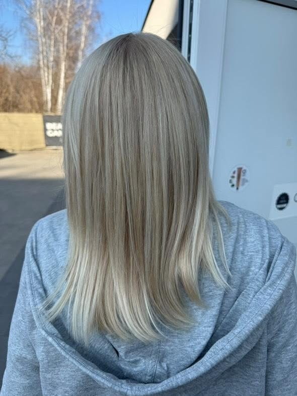 Włosy blond z delikatnym ombre, widoczne od tyłu, po zabiegu koloryzacji. Włosy proste, zadbane, z subtelnym przejściem kolorów. Ujęcie w dziennym świetle.