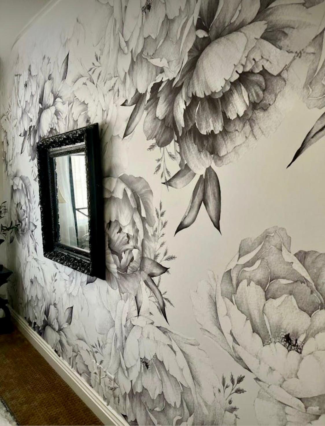 Ściana z fototapetą w kwiaty, z ramą lustra. Czarno-biała grafika z motywem roślinnym tworzy unikalny wystrój wnętrza.