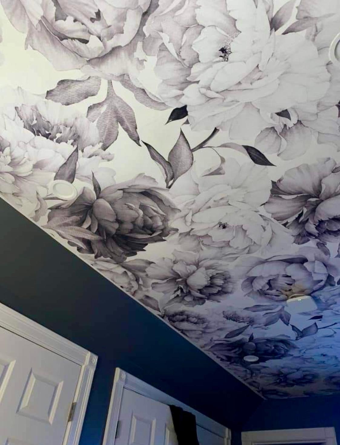 Kwiatowa tapeta na skośnym suficie w Piasecznie, z widocznymi drzwiami i ciemną ścianą. Detal wnętrza po remoncie, wzór w odcieniach szarości.