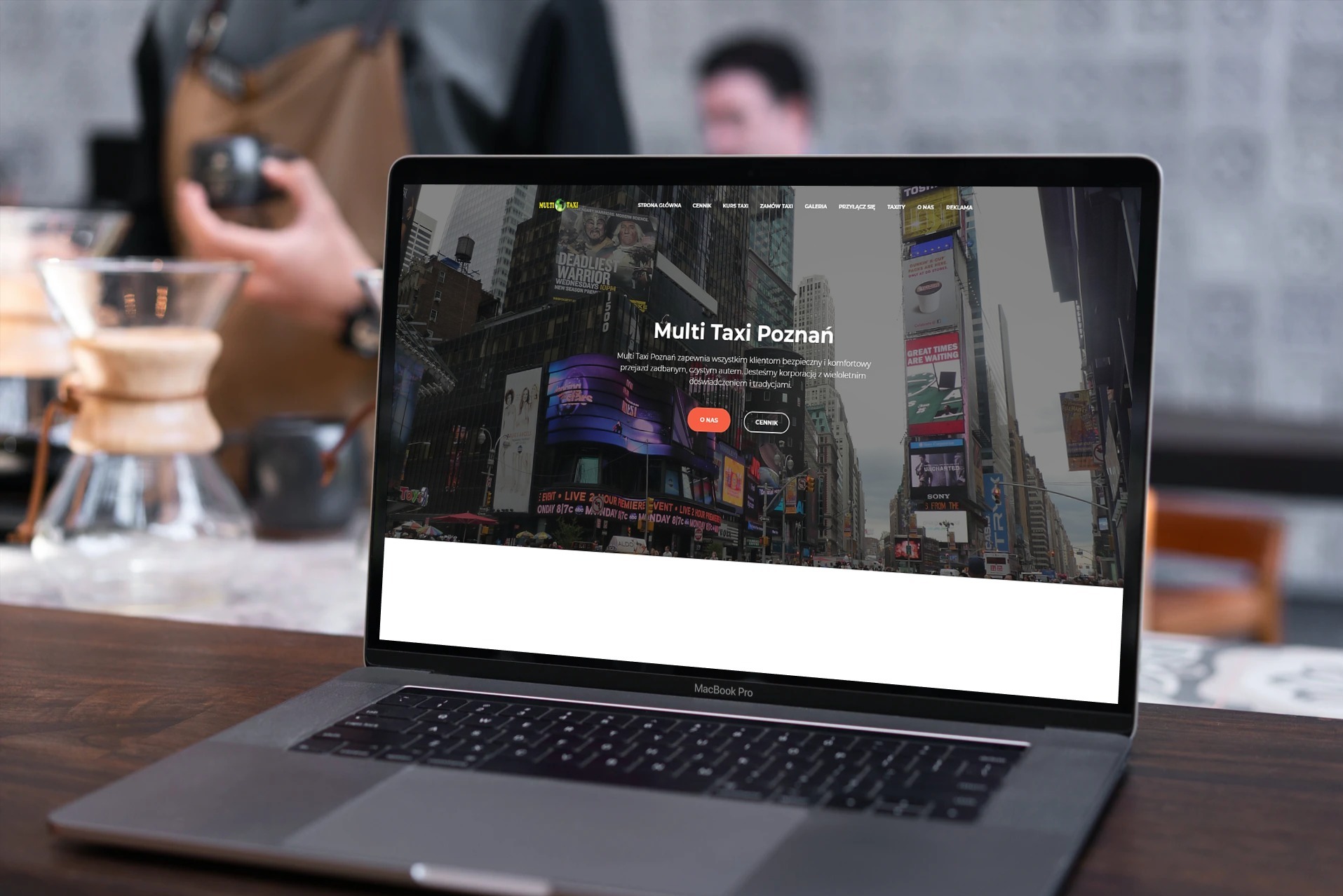 Laptop MacBook Pro prezentuje stronę Multi Taxi Poznań z Times Square w tle. Widoczne elementy strony: menu, przyciski, tekst informacyjny i logo firmy.