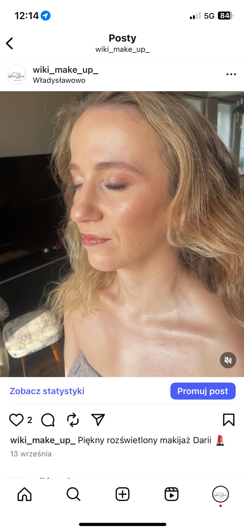 Portret kobiety z delikatnym, rozświetlonym makijażem w odcieniach różu i złota. Widoczne podkreślone kości policzkowe i błyszczące usta. Blond włosy opadają falami.