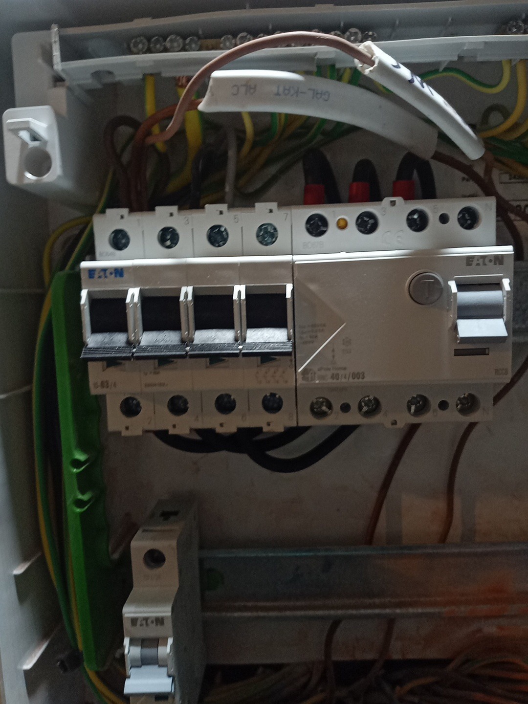 Rozdzielnica elektryczna marki Eaton z widocznymi bezpiecznikami i przewodami wewnątrz skrzynki. Widoczne oznaczenia na elementach.