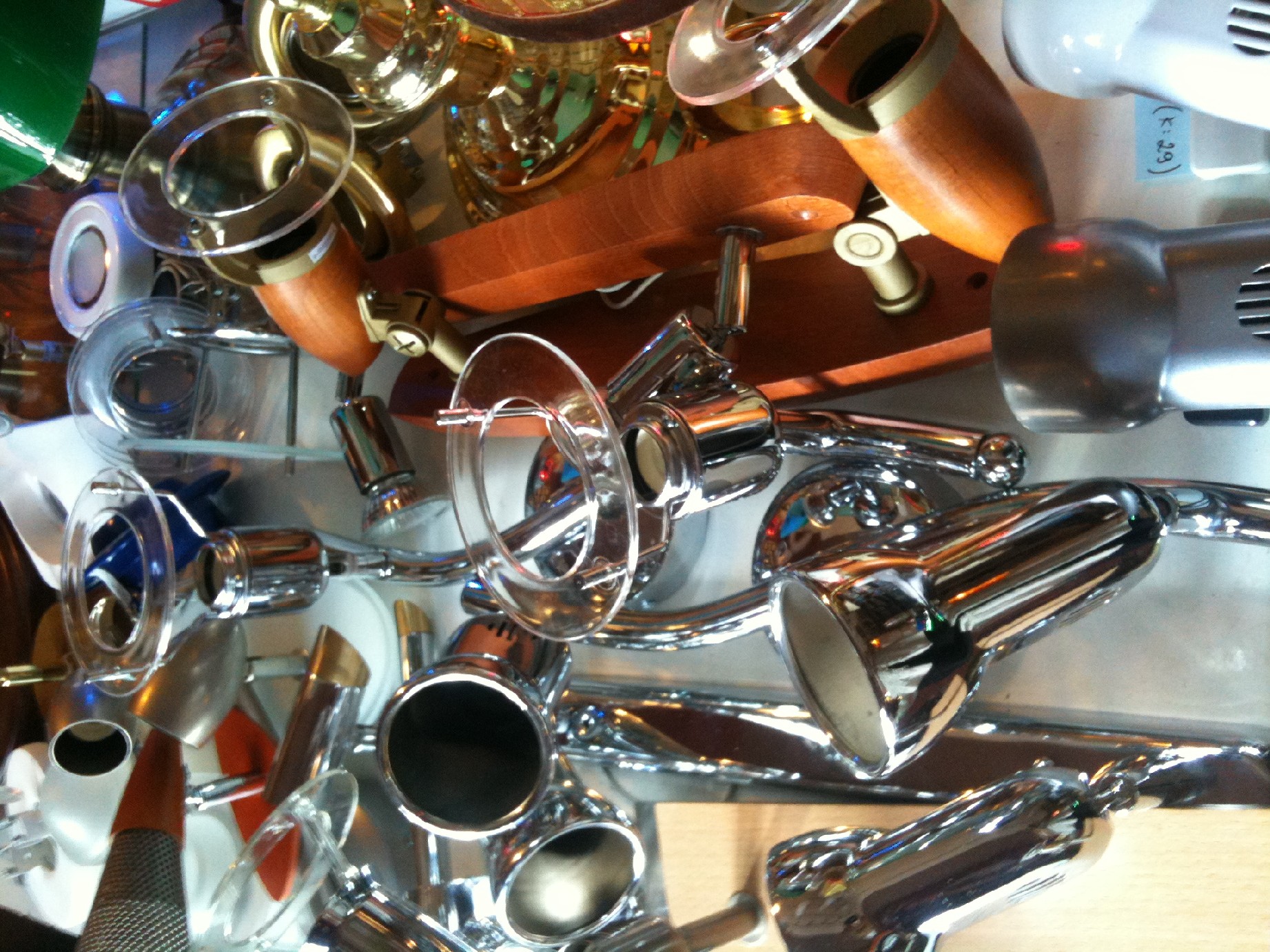 Różnorodny asortyment lamp: chromowane reflektory punktowe, drewniane lampy sufitowe i inne modele w sklepie.