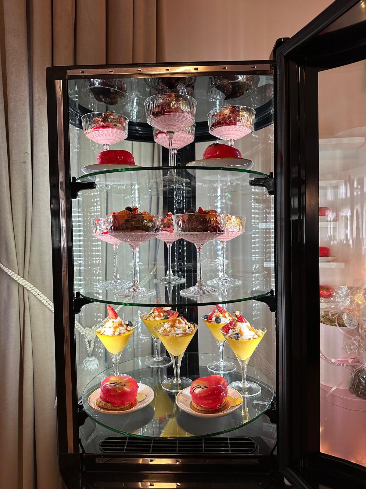 Elegancka witryna chłodnicza z deserami w szklanych naczyniach, prezentacja słodkości w cukierni w Poznaniu. Różnorodne desery owocowe i kremowe.