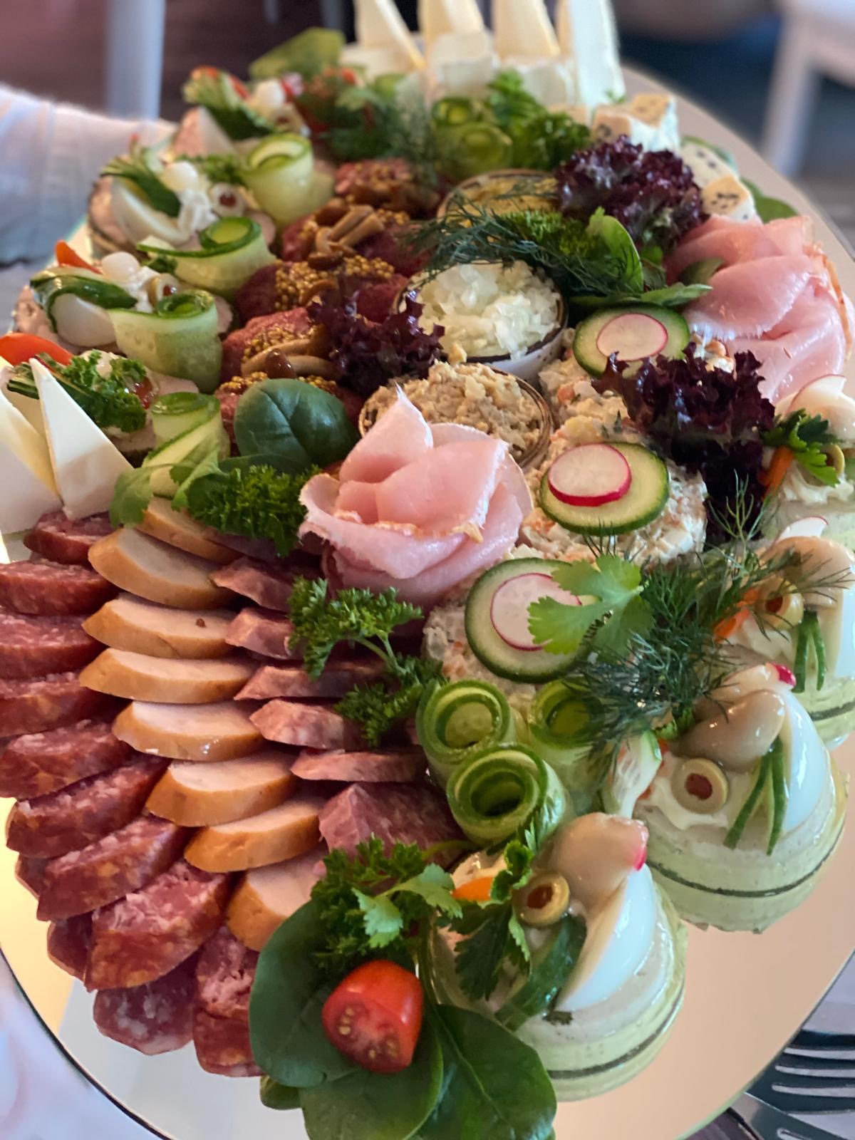 Elegancka taca z wykwintnymi przekąskami: wędliny, sery, warzywa, sałatki. Dekoracyjne ułożenie, świeże zioła. Idealne na przyjęcie.