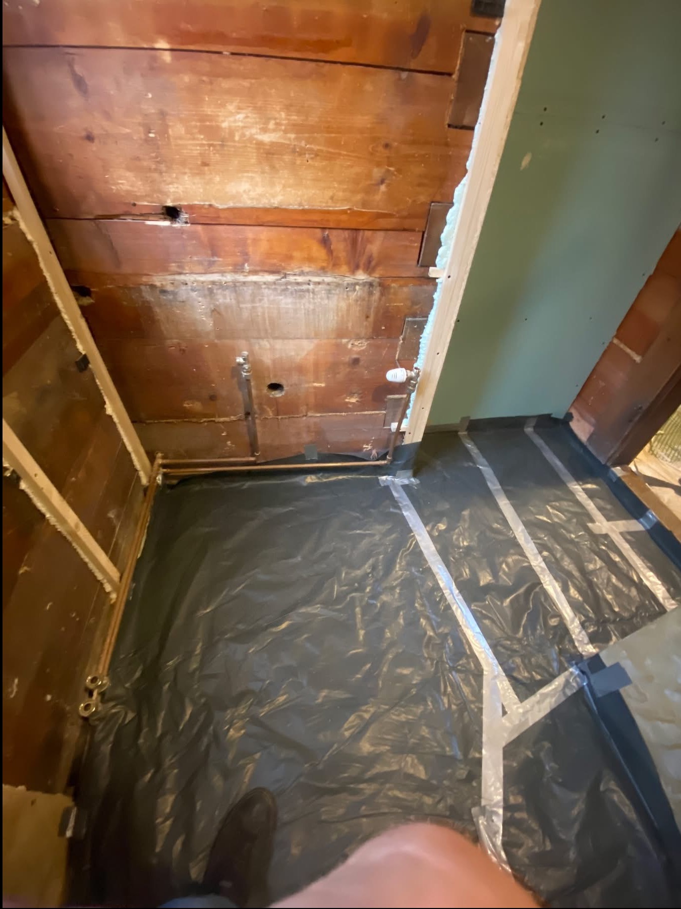 Przygotowanie do montażu płyty karton gips: drewniana konstrukcja, izolacja pianką, folia ochronna na podłodze, widoczne rury. Ujęcie z góry, podkreślające etap prac.