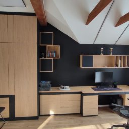 Serhii Kalataliuk - Pokój na poddaszu z zabudową meblową: szafa, biurko z szufladami i półki w odcieniach drewna z czarnymi akcentami. Widoczne drewniane belki stropowe i okno.