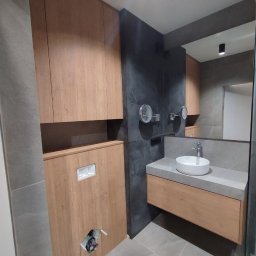 Serhii Kalataliuk - Nowoczesna łazienka z drewnianą zabudową meblową, szarą płytką i okrągłą umywalką. Widoczne lustra i oświetlenie punktowe.