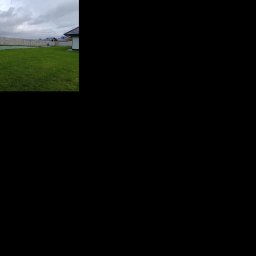 Bartłomiej Monica OGRO-TECH - Długi, jasny płot betonowy, z widocznymi słupkami, otacza zielony trawnik przed domem. Pochmurne niebo w tle. Ujęcie z niskiej perspektywy.